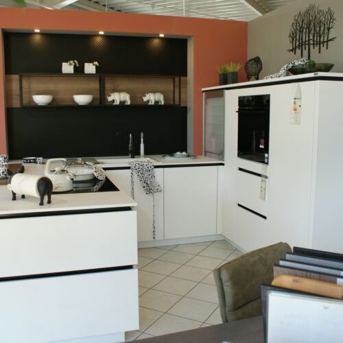 Moderne Küche mit weißen Schränken, Dekoration in Schwarz-Weiß, Pflanzen und orangenen Akzenten.
