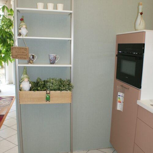Ein Regal mit Deko: zwei Gartenzwerge, Pflanzen, Tassen, vor mintfarbener Wand, links Pflanzen.