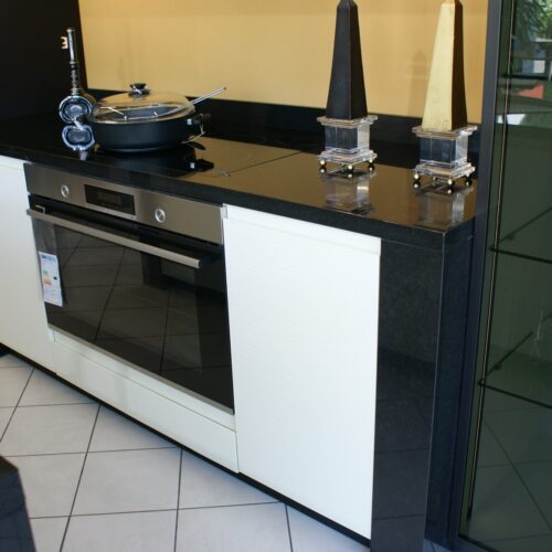 Moderne Küche mit schwarzer Arbeitsplatte, weißem Ofen und glänzenden Dekorationen.