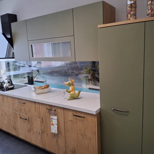 Moderne Küche mit grünen und holzfarbenen Schränken sowie einer Drachenfigur auf der Arbeitsplatte
